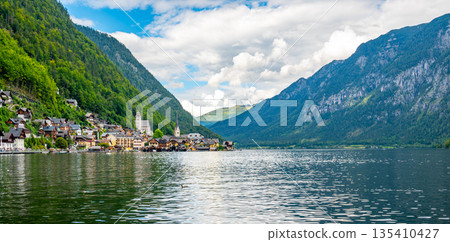 Famous Hallstatt city panorama with typical church near the Hallstatter see. Dramatic clouds on the sky. Famous tourist destination in Austria. 135410427