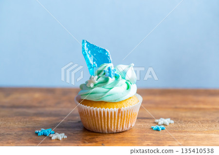 Homemade cupcake of blue color placed on wooden desk. Winter and christmas theme, snowflakes on cream with blue ice. Fresh and home baked sweet. Homemade cupcake of blue color placed on wooden desk. Winter and christmas theme, snowflakes on cream with blue ice. Fresh and home baked sweet. 135410538
