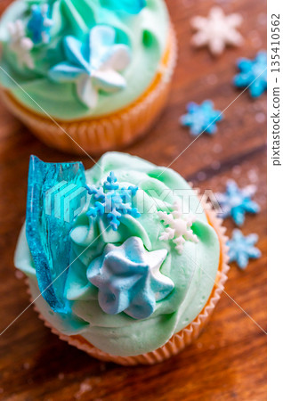 Homemade cupcake of blue color placed on wooden desk. Winter and christmas theme, snowflakes on cream with blue ice. Fresh and home baked sweet. 135410562