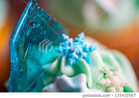 Homemade cupcake of blue color placed on wooden desk. Winter and christmas theme, snowflakes on cream with blue ice. Fresh and home baked sweet. Homemade cupcake of blue color placed on wooden desk. Winter and christmas theme, snowflakes on cream with blue ice. Fresh and home baked sweet. 135410567