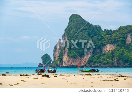 Landscape view of coastline with limestone rock and boats on ocean at Ko Phi Phi islands, Thailand. Concept of exotic tropical vacation and beautiful nature in paradise 135410743