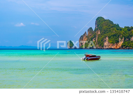 Landscape view of coastline with limestone rock and boats on ocean at Ko Phi Phi islands, Thailand. Concept of exotic tropical vacation and beautiful nature in paradise 135410747