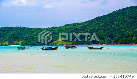 Landscape view of coastline with limestone rock and boats on ocean at Ko Phi Phi islands, Thailand. Concept of exotic tropical vacation and beautiful nature in paradise 135410749