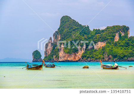 Landscape view of coastline with limestone rock and boats on ocean at Ko Phi Phi islands, Thailand. Concept of exotic tropical vacation and beautiful nature in paradise 135410751
