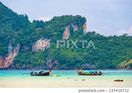 Landscape view of coastline with limestone rock and boats on ocean at Ko Phi Phi islands, Thailand. Concept of exotic tropical vacation and beautiful nature in paradise 135410752