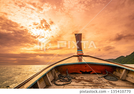 View from long tail boat heading to the dramatic sunset above ocean. Concept of exotic vacation in tropical paradise. Photo taken at Thailand near Ko Phi Phi islands. 135410770