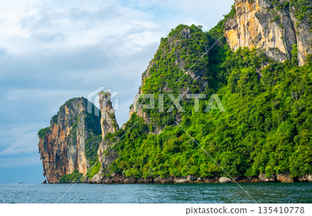 View of limestone rock at Ko Phi Phi islands, Thailand. View from long tailed boat. Exotic and tropic nature, summer paradise. View of limestone rock at Ko Phi Phi islands, Thailand. View from long tailed boat. Exotic and tropic nature, summer paradise. 135410778