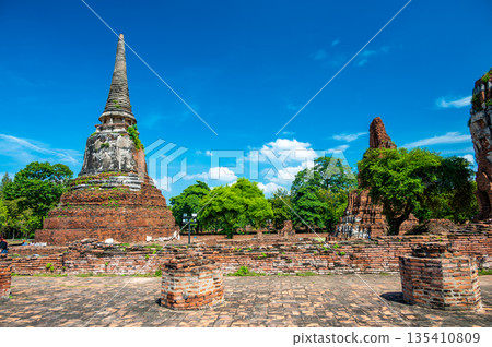 Ruins of ancient city and temples Ayutthaya, Thailand. Old kingdom of Siam. Summer day with blue sky. Famous tourist destination, spiritual place near Bangkok. Ruins of ancient city and temples Ayutthaya, Thailand. Old kingdom of Siam. Summer day with blue sky. Famous tourist destination, spiritual place near Bangkok. 135410809
