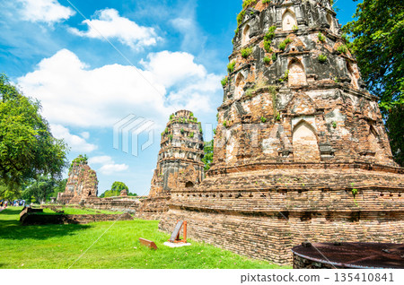 Ruins of ancient city and temples Ayutthaya, Thailand. Old kingdom of Siam. Summer day with blue sky. Famous tourist destination, spiritual place near Bangkok. Ruins of ancient city and temples Ayutthaya, Thailand. Old kingdom of Siam. Summer day with blue sky. Famous tourist destination, spiritual place near Bangkok. 135410841