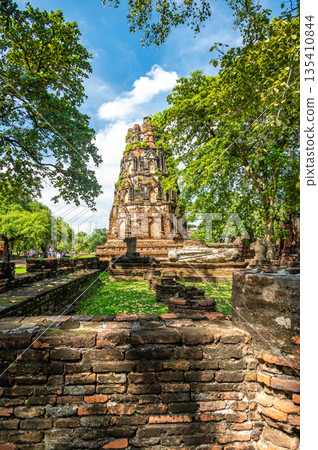 Ruins of ancient city and temples Ayutthaya, Thailand. Old kingdom of Siam. Summer day with blue sky. Famous tourist destination, spiritual place near Bangkok. Ruins of ancient city and temples Ayutthaya, Thailand. Old kingdom of Siam. Summer day with blue sky. Famous tourist destination, spiritual place near Bangkok. 135410844