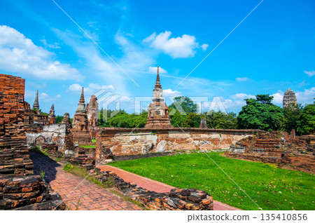 Ruins of ancient city and temples Ayutthaya, Thailand. Old kingdom of Siam. Summer day with blue sky. Famous tourist destination, spiritual place near Bangkok. 135410856