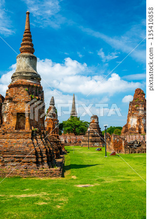 Ruins of ancient city and temples Ayutthaya, Thailand. Old kingdom of Siam. Summer day with blue sky. Famous tourist destination, spiritual place near Bangkok. 135410858