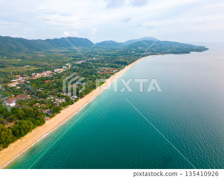 Aerial drone view of Koh Lanta island - the long beach. Famous tropical beach with white sand and turquoise ocean. The island mountains in background. Aerial drone view of Koh Lanta island - the long beach. Famous tropical beach with white sand and turquoise ocean. The island mountains in background. 135410926
