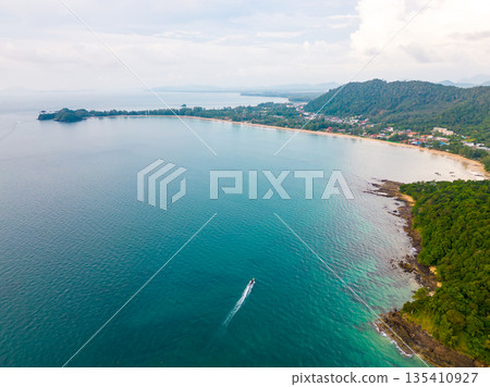 Aerial drone view of Koh Lanta island - the long beach. Famous tropical beach with white sand and turquoise ocean. The island mountains in background. Aerial drone view of Koh Lanta island - the long beach. Famous tropical beach with white sand and turquoise ocean. The island mountains in background. 135410927