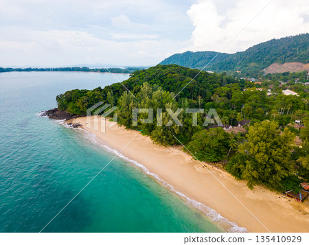 Aerial drone view of Koh Lanta island - the long beach. Famous tropical beach with white sand and turquoise ocean. The island mountains in background. 135410929