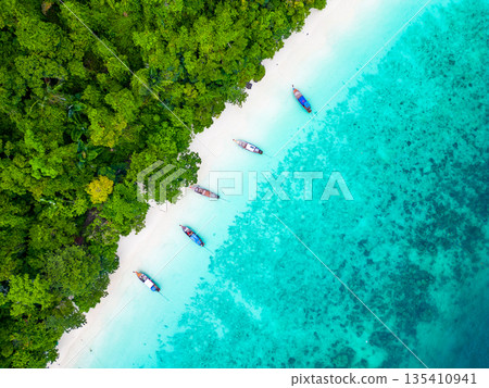 Aerial drone view of famous Monkey Beach at Ko Phi Phi island, Thailand. Tropical beach with white sand, turquoise water and green forest. Long tailed boats are waiting on beach. Exotic tourist 135410941