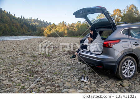 Woman Relaxing in Car Trunk in Nature Woman Relaxing in Car Trunk in Nature 135411022