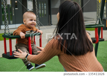Mother and Baby on Swing in Playground Mother and Baby on Swing in Playground 135411026