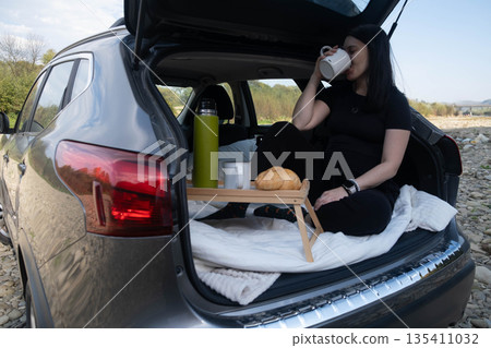 Woman Relaxing in Car Trunk in Nature Woman Relaxing in Car Trunk in Nature 135411032