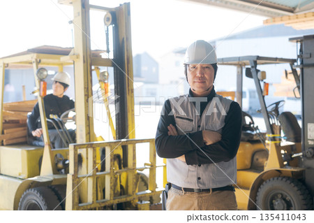 一名男工人站在一輛堆高機前 135411043