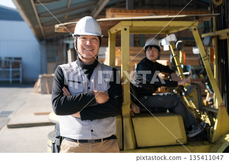 Male worker standing in front of a forklift 135411047
