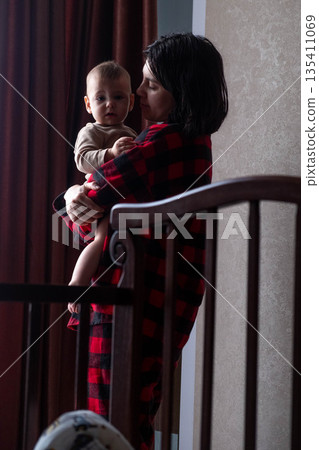 Mother Holding Baby in Dimly Lit Room 135411069