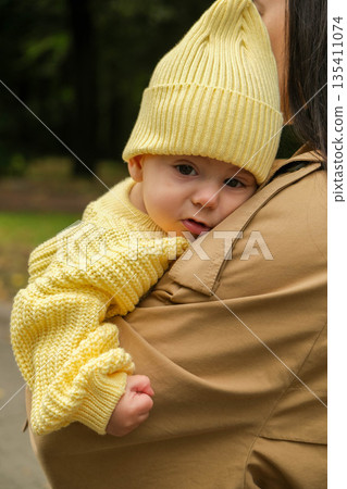 Mother Holding Baby in Yellow Outfit at Park Mother Holding Baby in Yellow Outfit at Park 135411074
