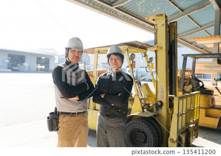 兩名工人站在一輛堆高機前 135411200