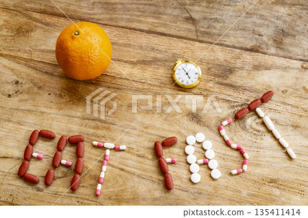 eat fast message with pills and half plate of food on table eat fast message with pills and half plate of food on table 135411414