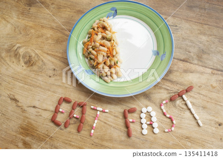 eat fast message with pills and half plate of food on table eat fast message with pills and half plate of food on table 135411418
