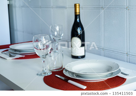 elegant dining table set for two with wine bottle and red placemats elegant dining table set for two with wine bottle and red placemats 135411503