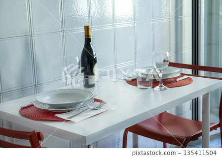 elegant dining table set for two with wine bottle and red placemats elegant dining table set for two with wine bottle and red placemats 135411504