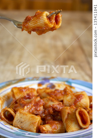 fork with rigatoni pasta with tomato sauce 135411841