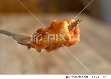 fork with rigatoni pasta with tomato sauce 135411842