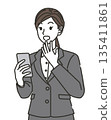 A woman in a suit surprised at her smartphone 135411861