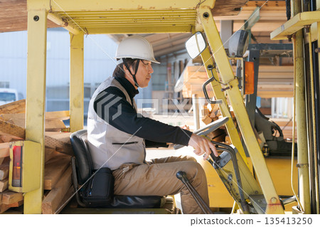 Worker operating a forklift 135413250