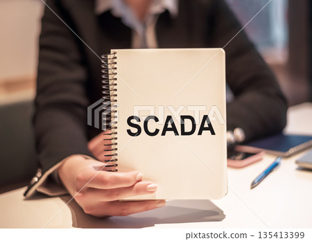 SCADA acronym for Supervisory Control and Data Acquisition text written in a notebook on the office desk SCADA acronym for Supervisory Control and Data Acquisition text written in a notebook on the office desk 135413399