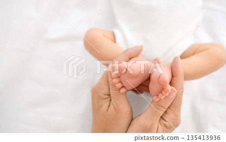 The small feet of a newborn baby , folded in the shape of a heart in the gentle hands of the mother 135413936