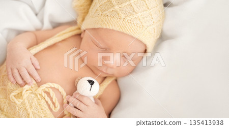 A newborn sleeping boy hugs a small soft toy. Baby's sound sleep A newborn sleeping boy hugs a small soft toy. Baby's sound sleep 135413938
