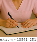A woman working as a caregiver takes notes in a notebook 135414251
