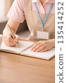A woman working as a caregiver takes notes in a notebook 135414252