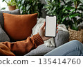Young Woman Relaxing on a Comfortable Sofa with Cellphone for Online Shopping and Communication 135414760