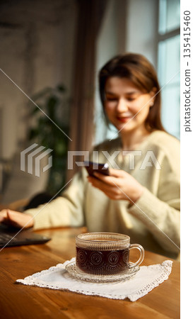 Coffee cup on wooden table with laptop and smartphone cozy remote work mood. Coffee cup on wooden table with laptop and smartphone cozy remote work mood. 135415460