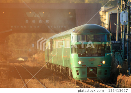 The limited express "Yufuin no Mori" (JR Kyushu) departs Bungomori Station bathed in the setting sun. 135415627