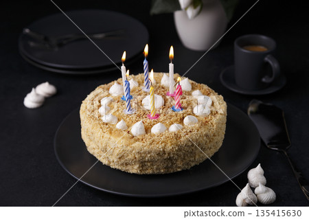 Whole holiday cake with crumbly shortcrust pastry and mini meringue. Birthday cake with lit candles.. Homemade baking. Black background, selective focus, close-up. 135415630