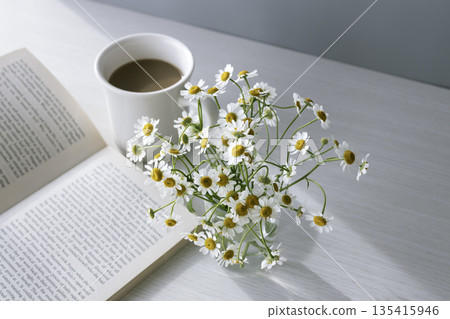 清晨，洋甘菊盛開，咖啡牛奶香醇－靜物：一本書和一張桌子 135415946