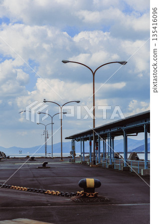 愛媛縣八幡濱港碼頭的廣角鏡頭。路燈和藍天。空曠的港口景色，遠處是連綿的山脈。 135416096