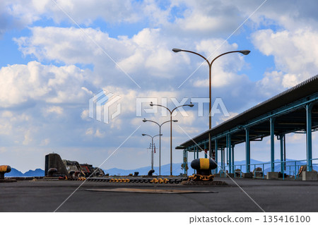 愛媛縣八幡濱港碼頭的廣角鏡頭。路燈和藍天。空曠的港口景色，遠處是連綿的山脈。 135416100