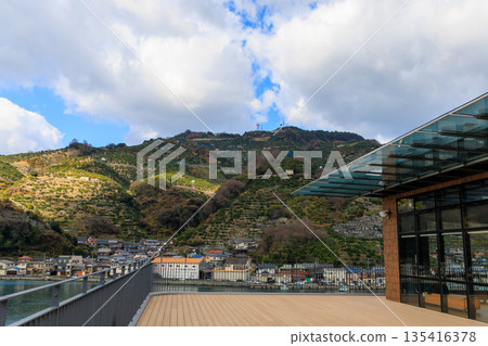 Modern building of Yawatahama Ferry Terminal in Ehime Prefecture, with glass-walled wooden deck and a view of Mt. Momiji. Scenery of port tourism facilities. Modern building of Yawatahama Ferry Terminal in Ehime Prefecture, with glass-walled wooden deck and a view of Mt. Momiji. Scenery of port tourism facilities. 135416378