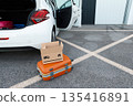 suitcases and boxes were lying on the ground next to the car. 135416891